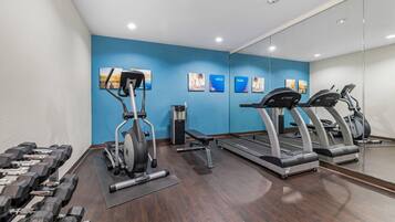 A gym with exercise equipment, including dumbbells, a stationary bike, and treadmills.