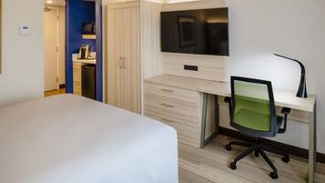 Een hotelkamer met een bed, een bureau met stoel, een televisie en een kledingkast.