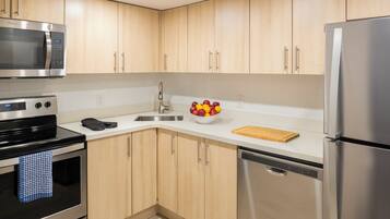 Een moderne keuken met roestvrijstalen apparatuur, houten kastjes en een schaal fruit op het aanrecht.
