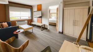 A hotel room with a sofa, a small table, a TV, a bed, a wardrobe, and a staircase. - Holiday Inn Express & Suites Halifax - Bedford by IHG (Halifax)