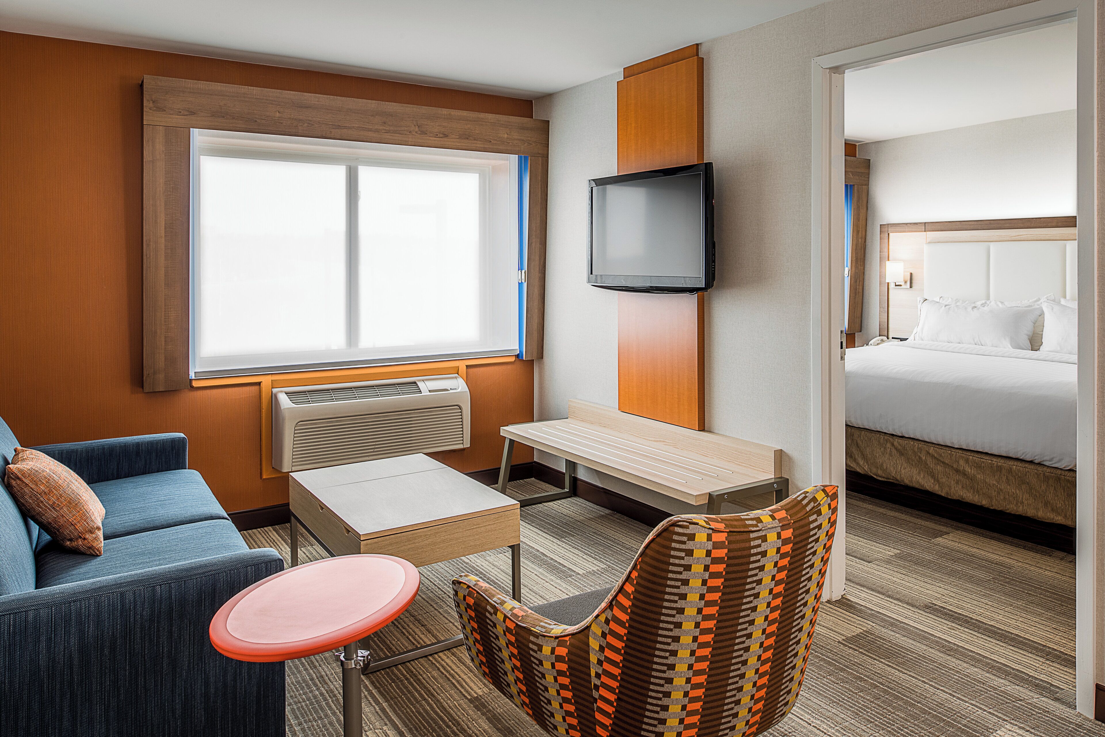 Ett hotellrum med en säng, en tv, en soffa, ett litet bord och en stol.