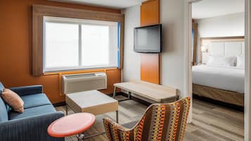 Ett hotellrum med en säng, en tv, en soffa, ett litet bord och en stol.