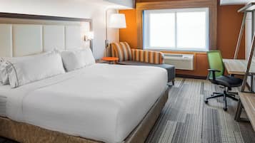 Une chambre d’hôtel avec un grand lit, une petite table, une chaise, un bureau et une fenêtre.