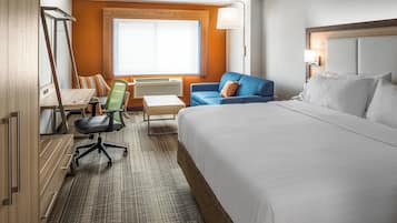 Una habitación de hotel con una cama grande, un escritorio con una silla, un sofá y una ventana con persianas.