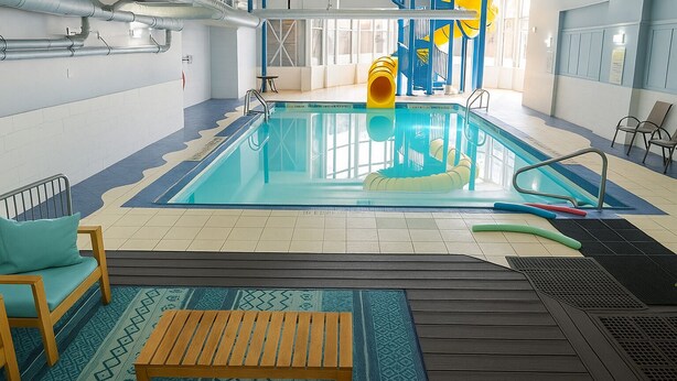 An indoor swimming pool with a slide, a wooden bench, and a patterned rug. - Holiday Inn Express & Suites Halifax - Bedford by IHG (Halifax)