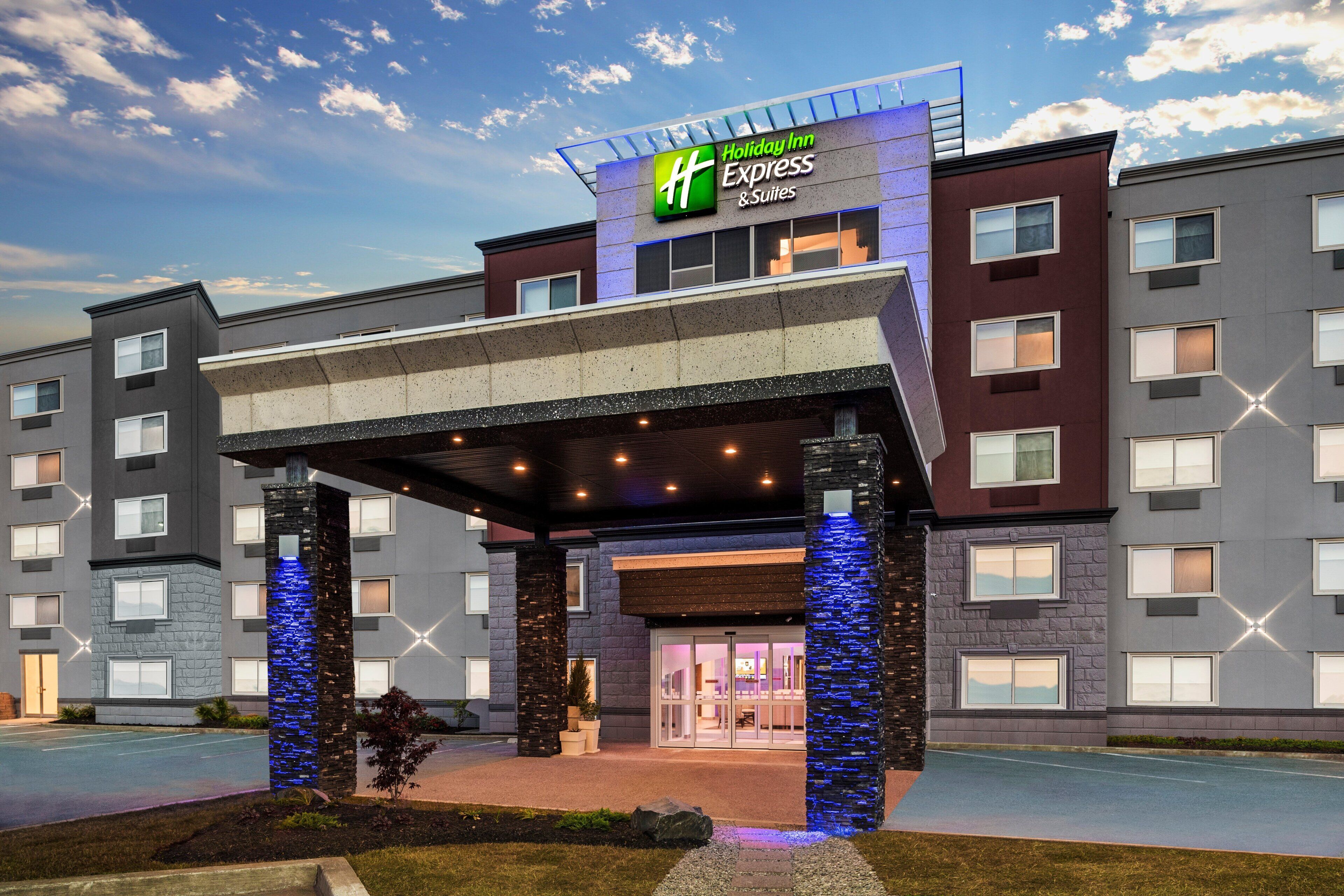 A Holiday Inn Express & Suites hotel entrance with a covered walkway and stone pillars.