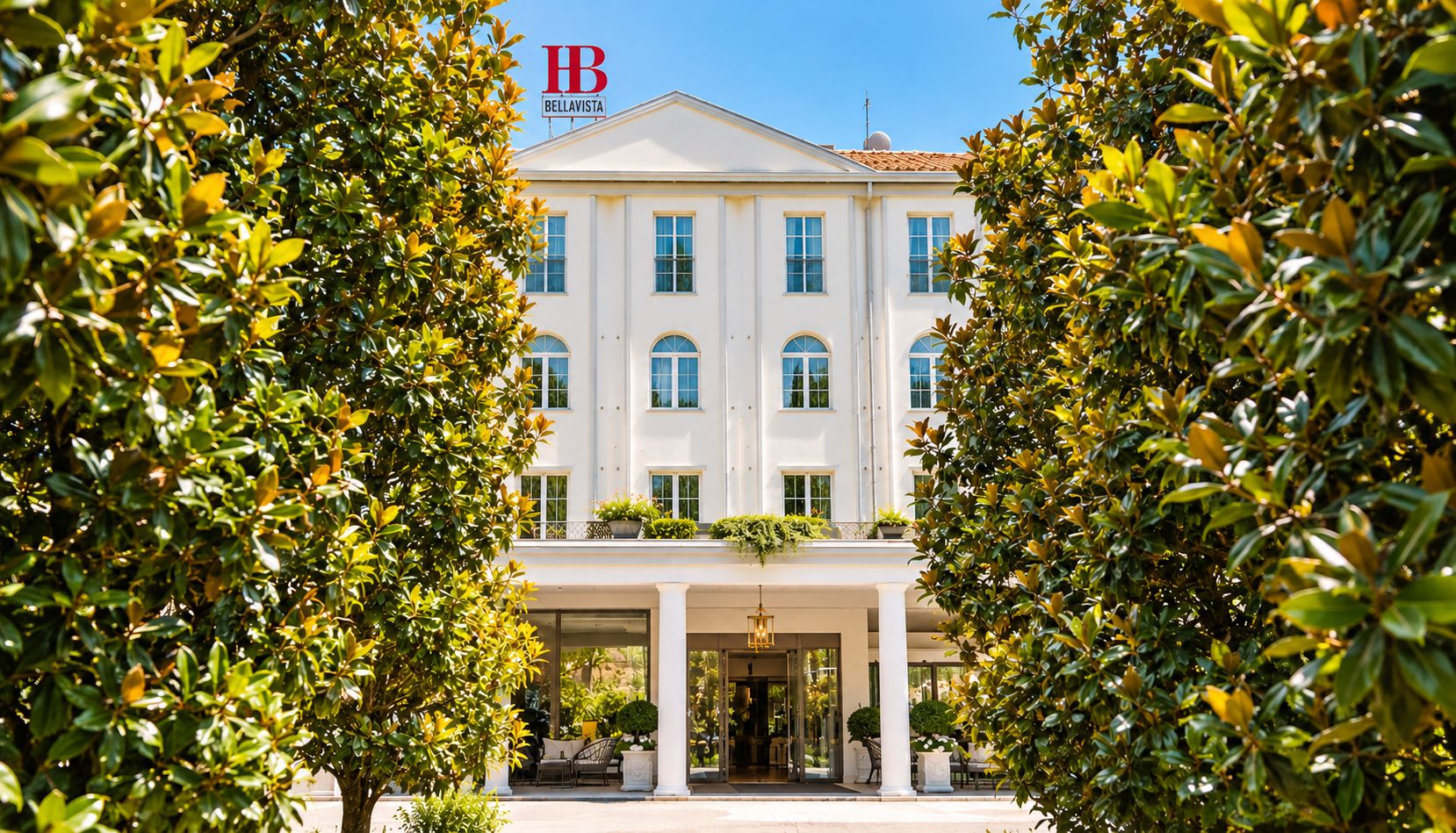 A white building with a sign reading 'HB Bellavista' and a balcony with plants.