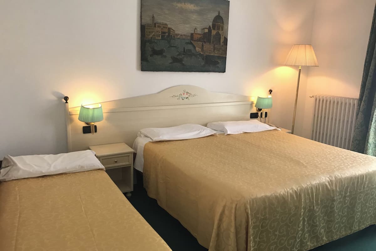 Een hotelkamer met twee bedden, een stadsgezicht op een schilderij en twee bedlampen.