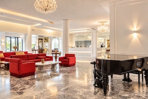 A spacious lobby with a grand piano, red upholstered sofas, and a marble floor. - Bellavista Terme Resort & Spa (Montegrotto Terme)