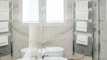 Un baño con un espejo grande, dos lavamanos, un inodoro y toalleros.