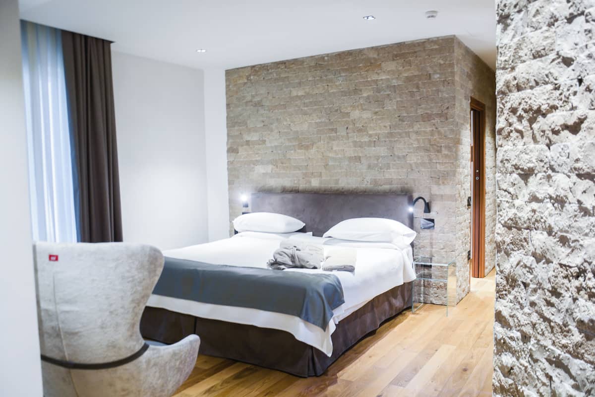 Een moderne hotelkamer met een groot bed, een accentmuur van baksteen en een houten vloer.