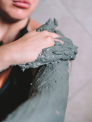 A close-up of a hand applying a gray, textured substance to a surface. - Bellavista Terme Resort & Spa (Montegrotto Terme)