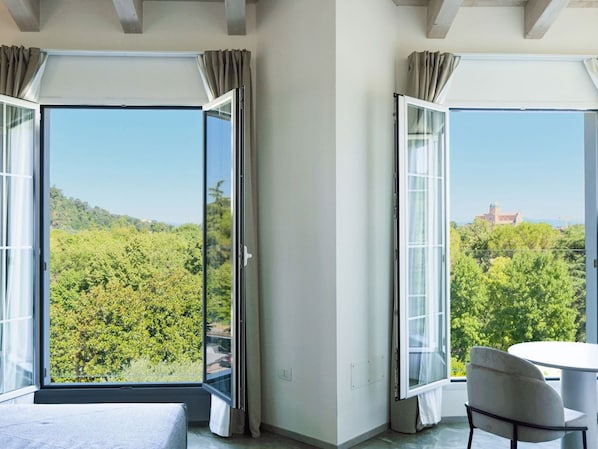 A room with a large sliding glass door leading to a balcony, a bed, and a round table with a chair. - Bellavista Terme Resort & Spa (Montegrotto Terme)
