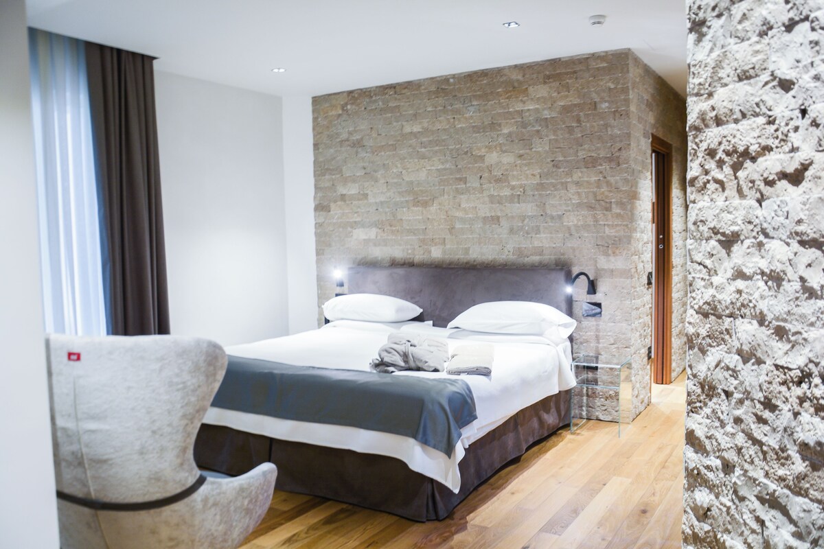 Een moderne hotelkamer met een groot bed, een accentmuur van baksteen en een houten vloer.