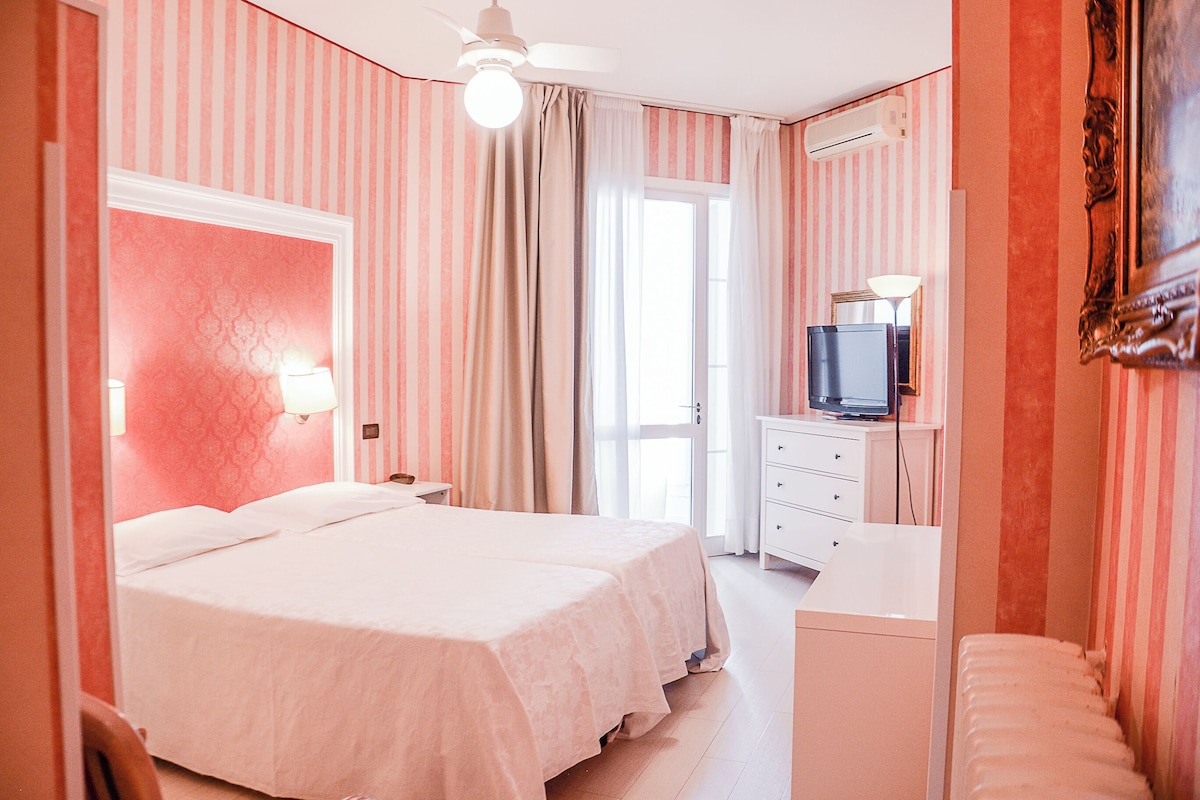 Een hotelkamer met een bed, een televisie, een bureau en een spiegel.