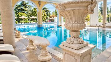 A pool area with stone columns and a large urn centerpiece.