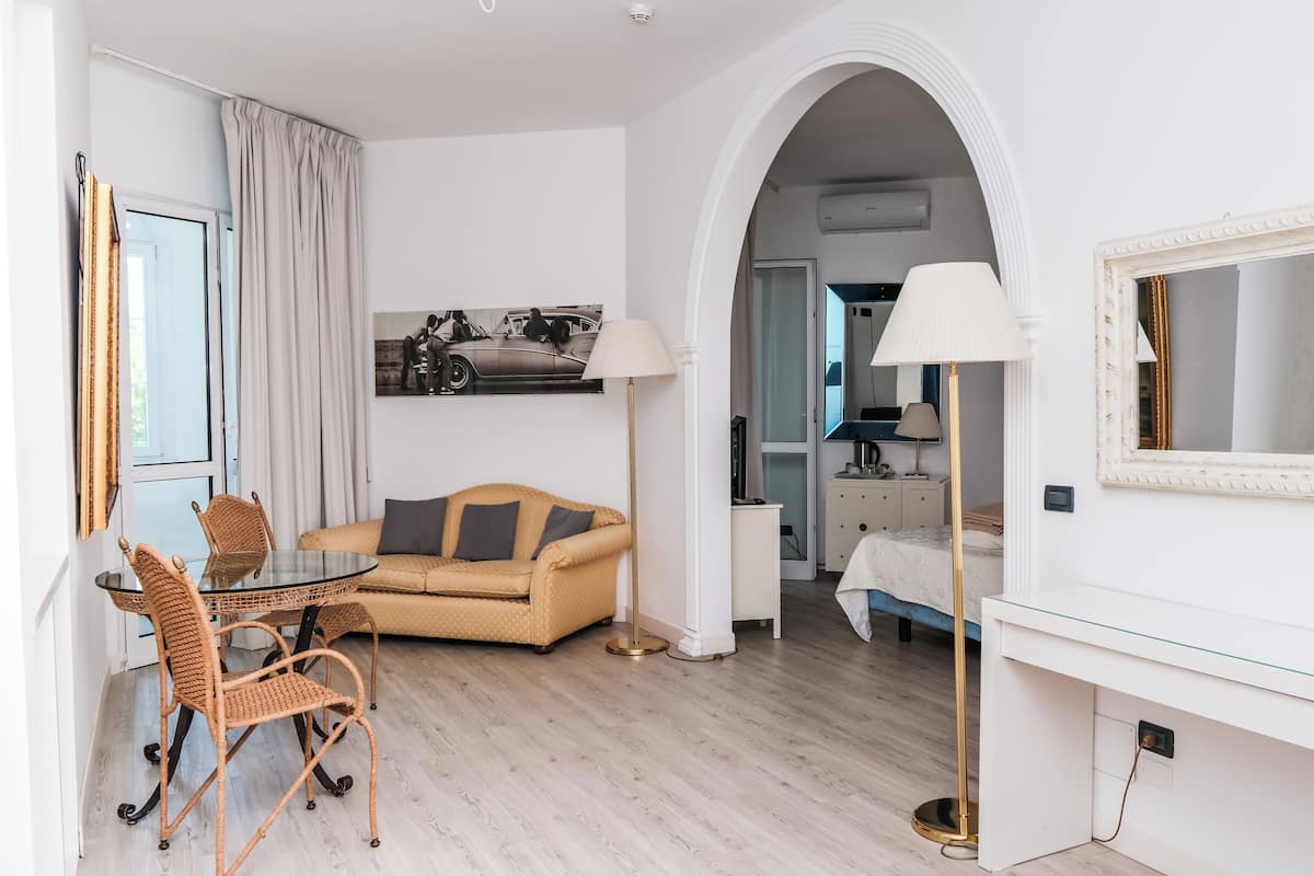 Een moderne hotelkamer met een zithoek, een bank, een bureau en een grote spiegel.