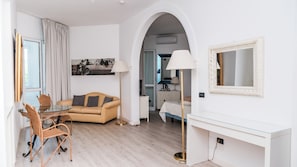 A modern hotel room with a dining area, a sofa, a desk, and a large mirror. - Bellavista Terme Resort & Spa (Montegrotto Terme)