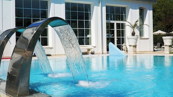 A swimming pool with a modern water feature in front.