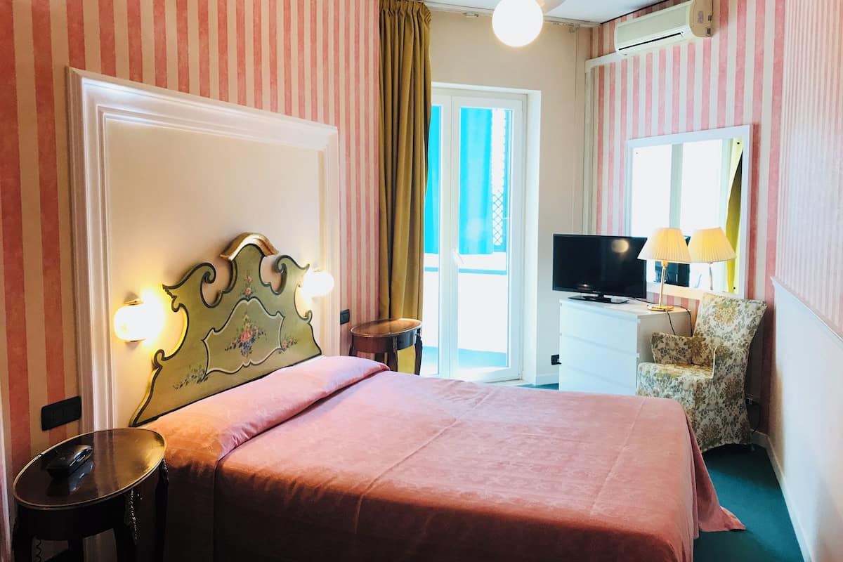 Een hotelkamer met een bed, een televisie, een bureau met een lamp en een stoel.