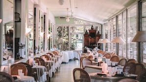 A restaurant with long tables, wicker chairs, and large windows. - Bellavista Terme Resort & Spa (Montegrotto Terme)
