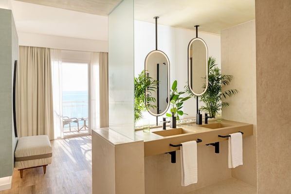 Un baño moderno con un espejo grande, dos lavamanos y un banco.