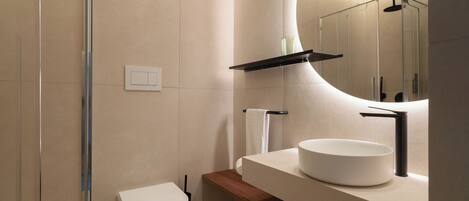 A modern bathroom with a glass shower enclosure, a white toilet, a wooden vanity, and a large mirror.