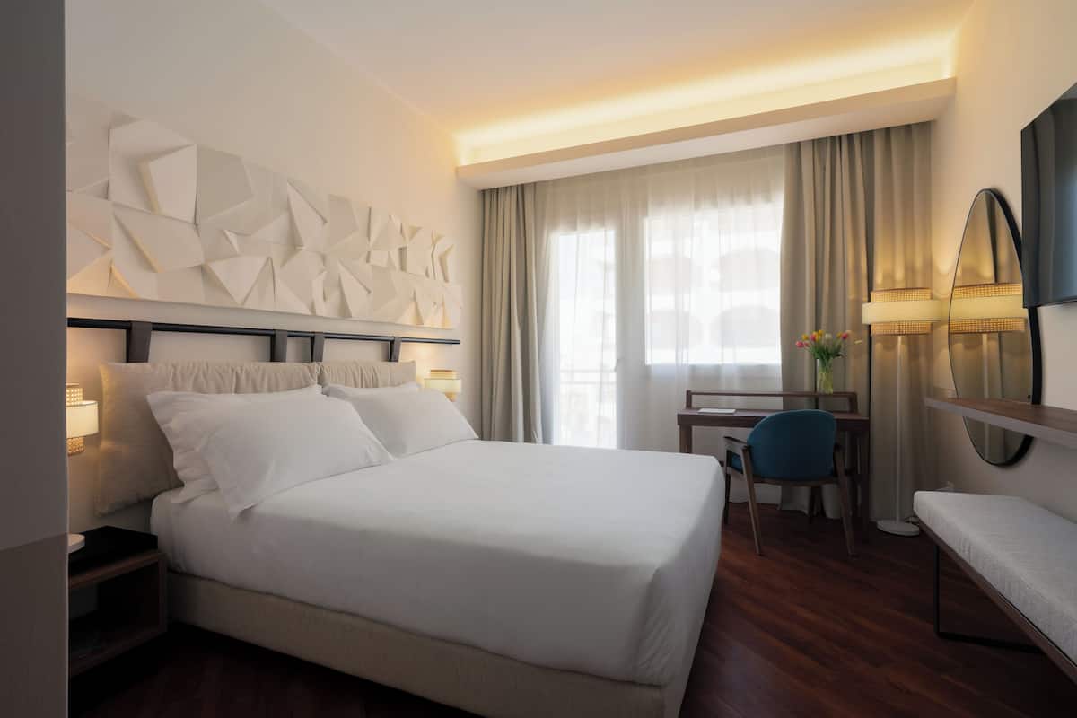 Une chambre d’hôtel moderne équipée d’un grand lit, d’un bureau, d’une chaise et d’un téléviseur.