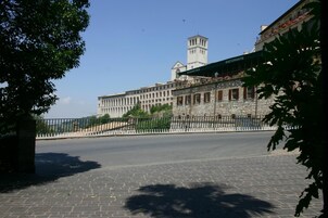 Um edifício histórico com fachada de pedra, uma torre e um restaurante chamado "Ristorante Giardino" no nível superior.