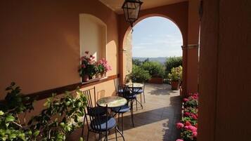 Eine Terrasse im Freien mit zwei runden Tischen und Stühlen, umgeben von Topfpflanzen und Blumen.