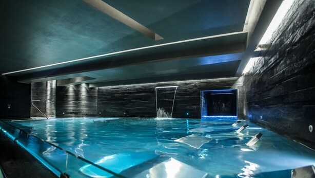 An indoor swimming pool with clear water, a glass barrier, and a dark, modern interior. - Hotel All Time Relais & Sport (Rome)