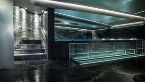 A modern, dimly lit interior with a staircase, a glass railing, and a concrete wall. - Hotel All Time Relais & Sport (Rome)