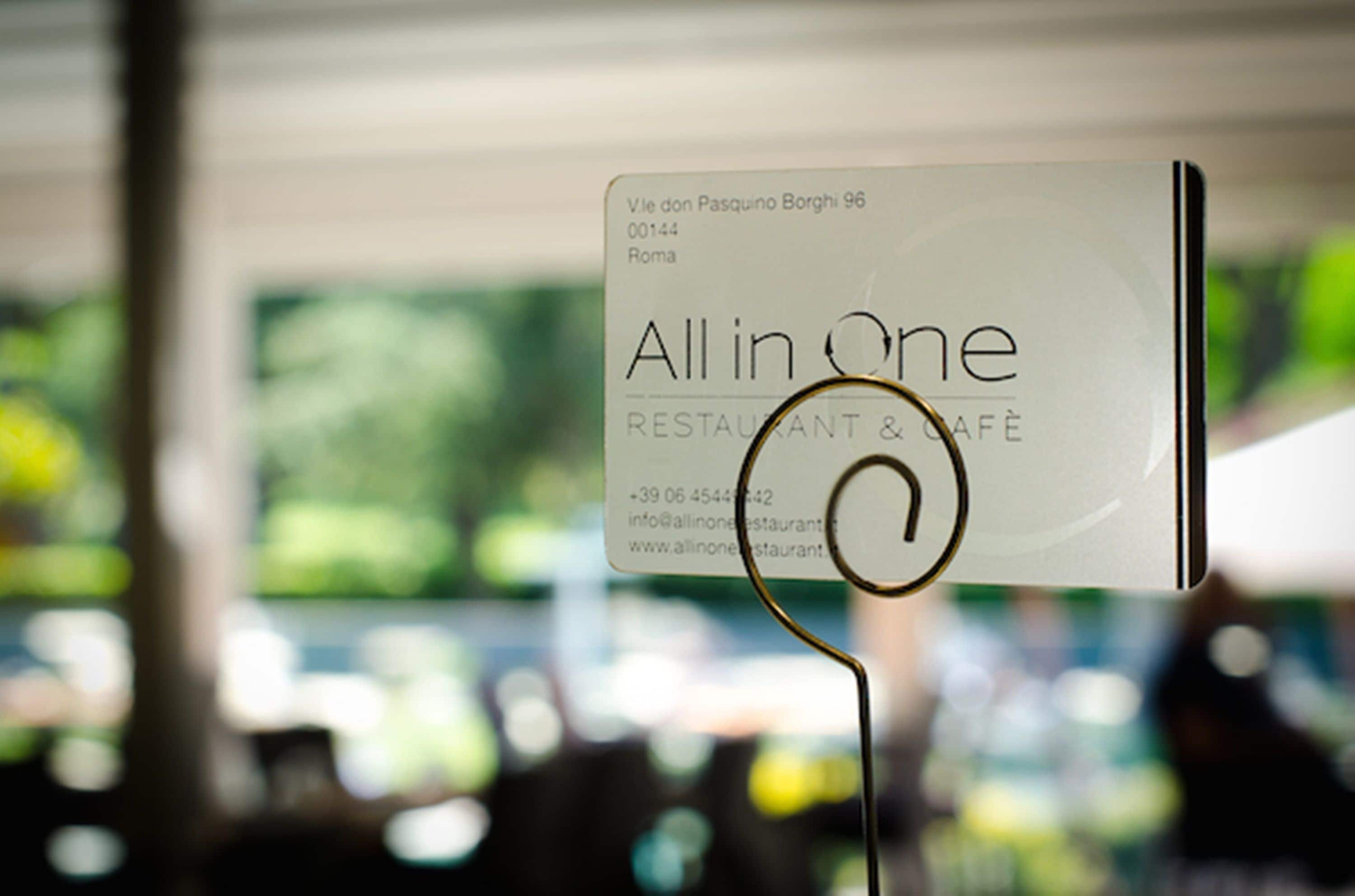 A restaurant sign with the name 'All in One' and contact information.