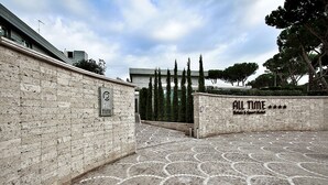 A courtyard with a tiled floor, a brick wall, and a sign that reads "ALL TIME". - Hotel All Time Relais & Sport (Rome)