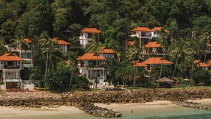 A coastal resort with multiple buildings, a rocky shoreline, and clear turquoise water. - Napasai Samui (Koh Samui)