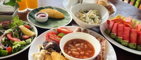 A table with various dishes including salad, beans, bacon, and fruit.