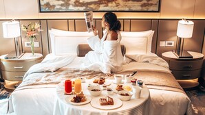 A hotel room with a bed, a breakfast table with food and drinks, a lamp, and a painting on the wall. - Shangri-La Eros, New Delhi (New Delhi)