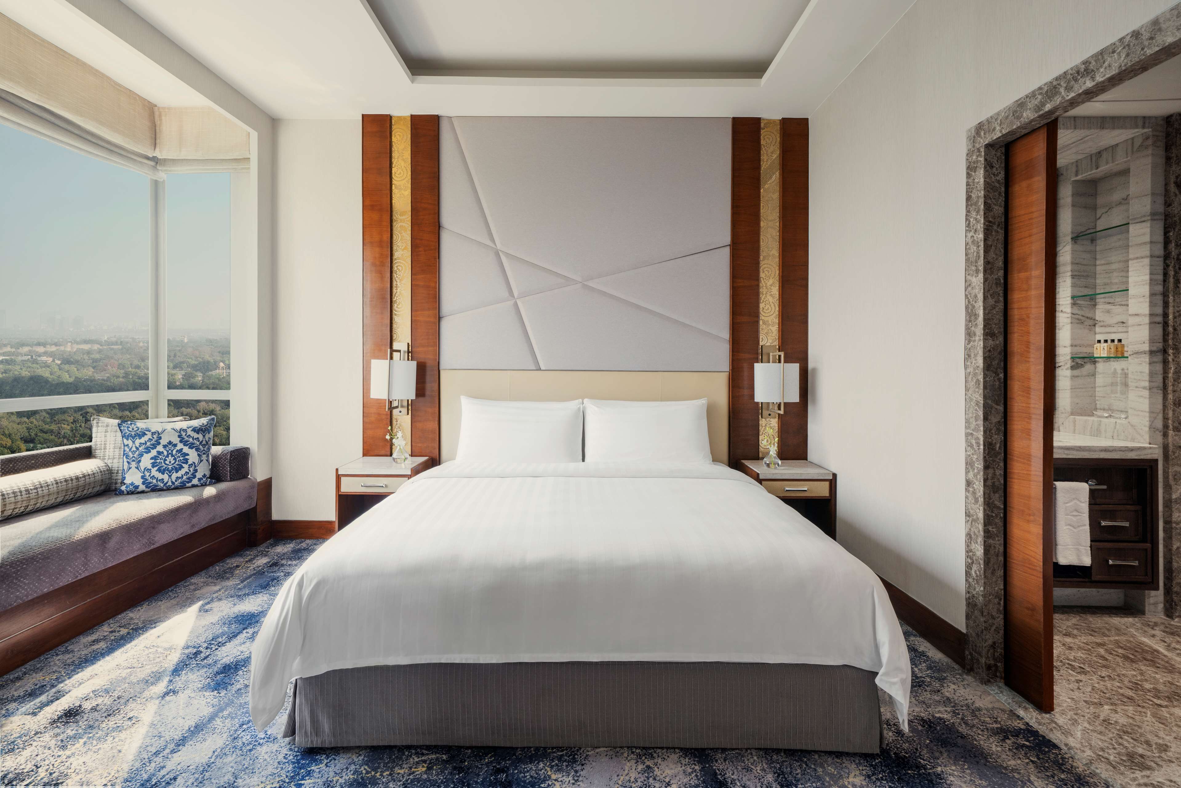 Une chambre d’hôtel dotée d’un grand lit, offrant une vue sur la ville, comprenant un coin salon avec vue et une salle de bain agrémentée de touches de marbre.