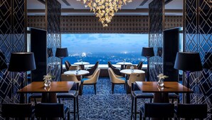 A restaurant with a view of the cityscape, featuring a chandelier, patterned walls, and modern furniture. - Shangri-La Eros, New Delhi (New Delhi)