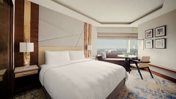 A hotel room with a large bed, a desk, a chair, a small table, and a view of the city.