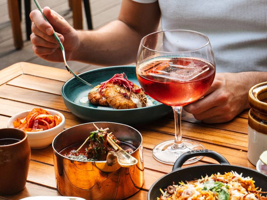 Una mesa de comedor con varios platos, incluyendo un tazón de arroz, una bandeja de comida y un vaso de bebida roja.