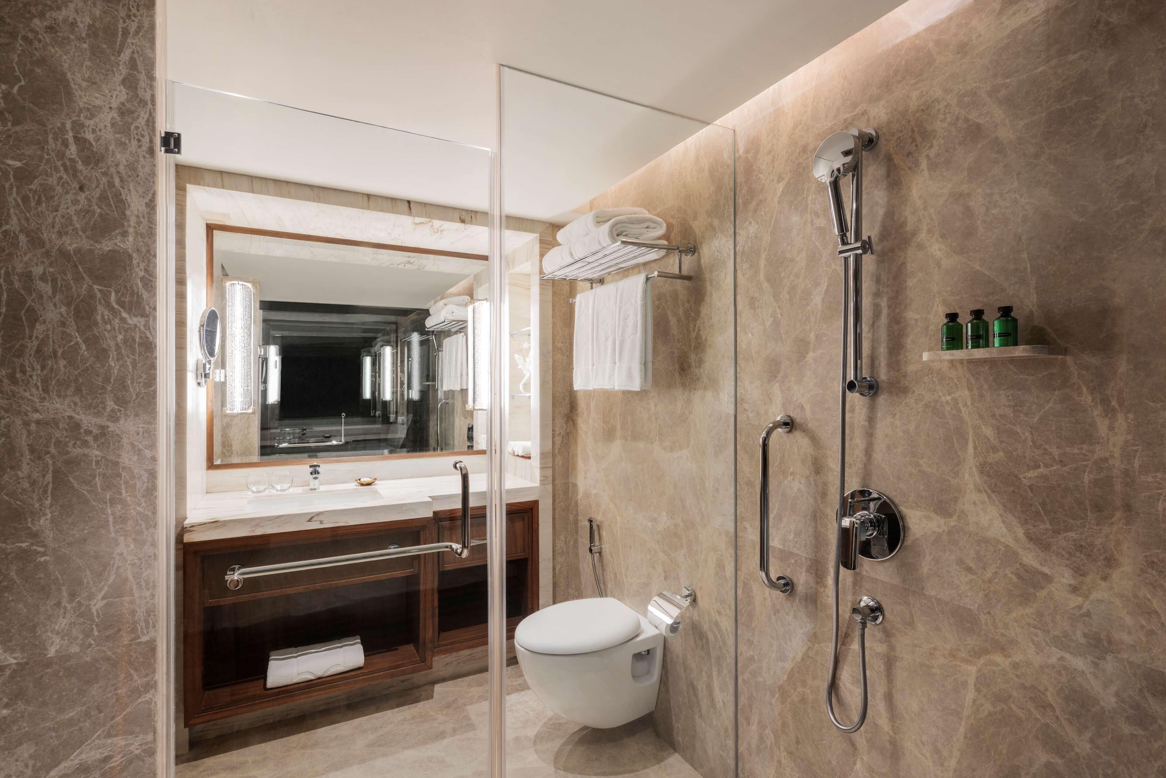 A modern bathroom with a glass-enclosed shower, a toilet, a vanity with a mirror, and a towel rack.