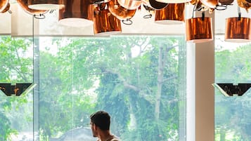 A dining area with a large window, a table with chairs, and hanging copper pots.