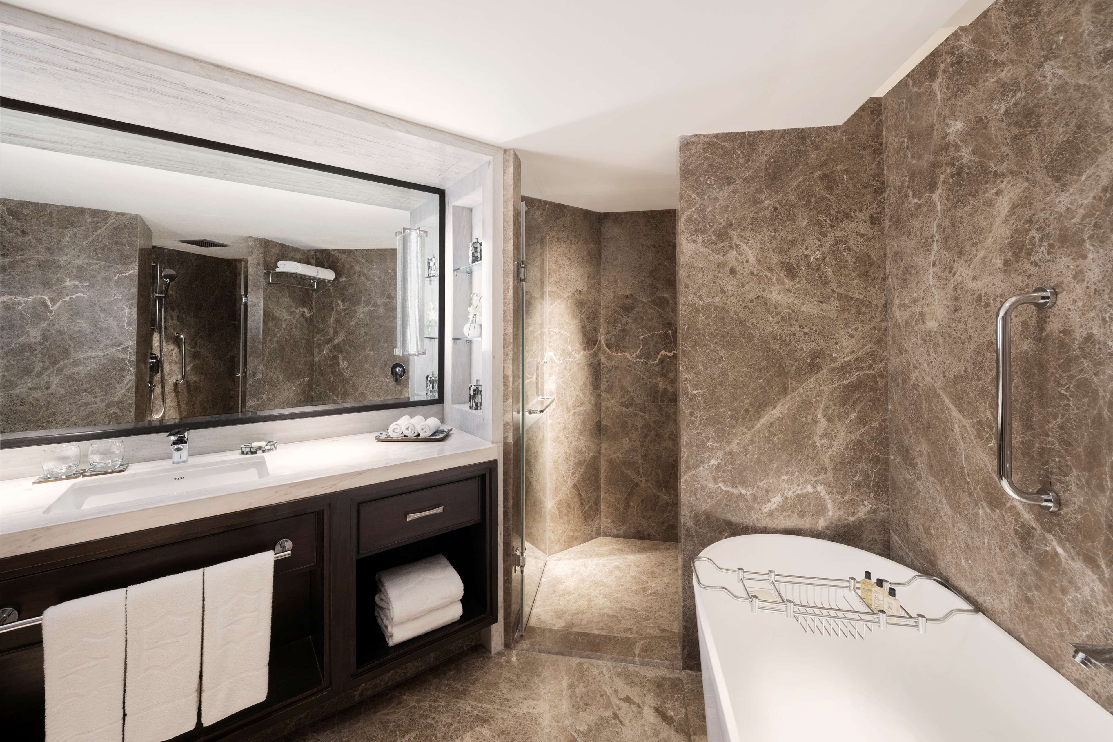 A modern bathroom with a large mirror, two sinks, a bathtub, and a shower area.