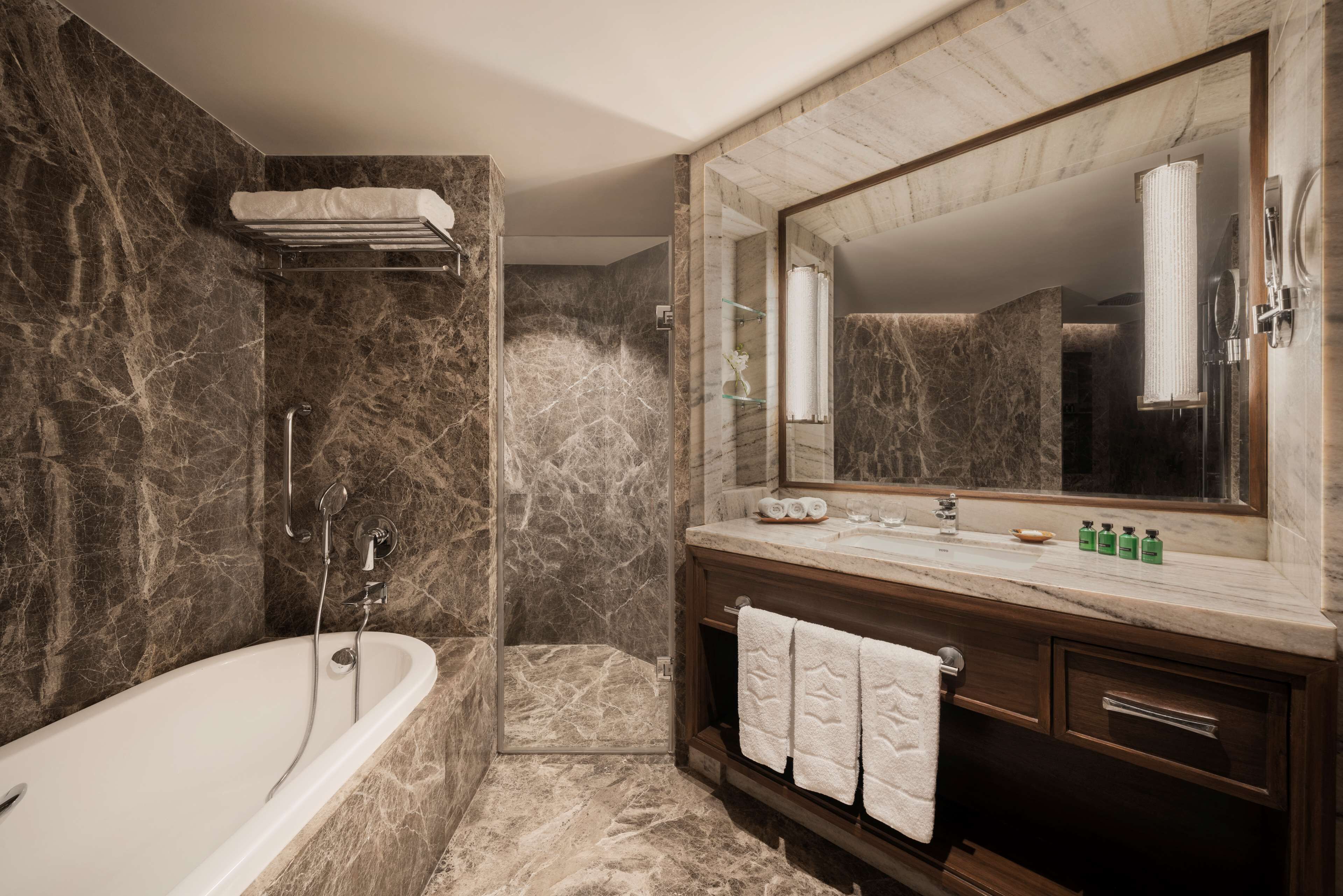 A modern bathroom with a marble shower, a freestanding bathtub, and a large mirror above the vanity.