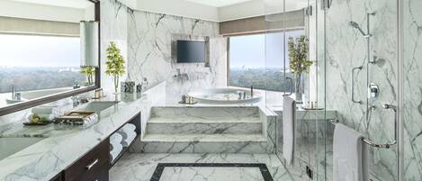 A luxurious bathroom with a marble floor, a large bathtub, a glass-enclosed shower, and a large mirror.