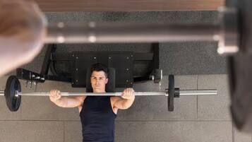 A person performing a bench press exercise on a gym bench with a barbell.