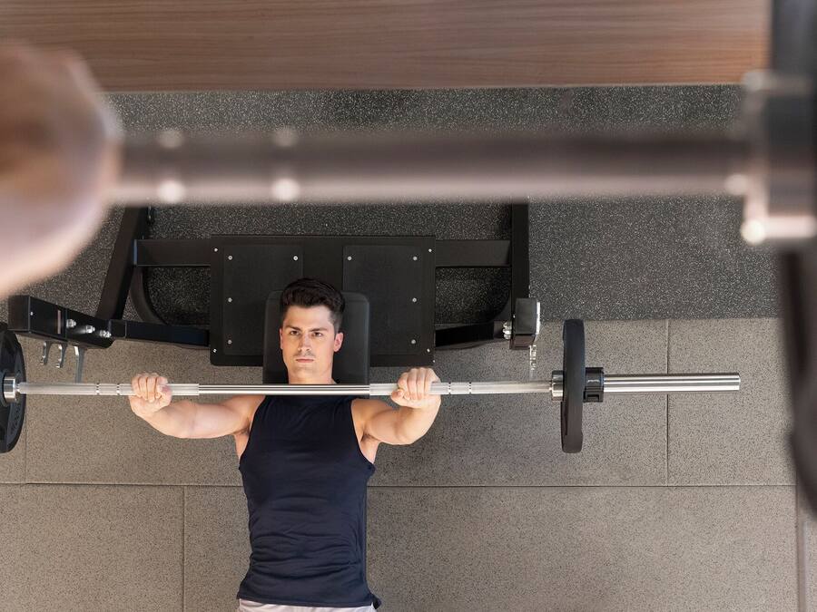 A person performing a bench press exercise on a gym bench with a barbell.