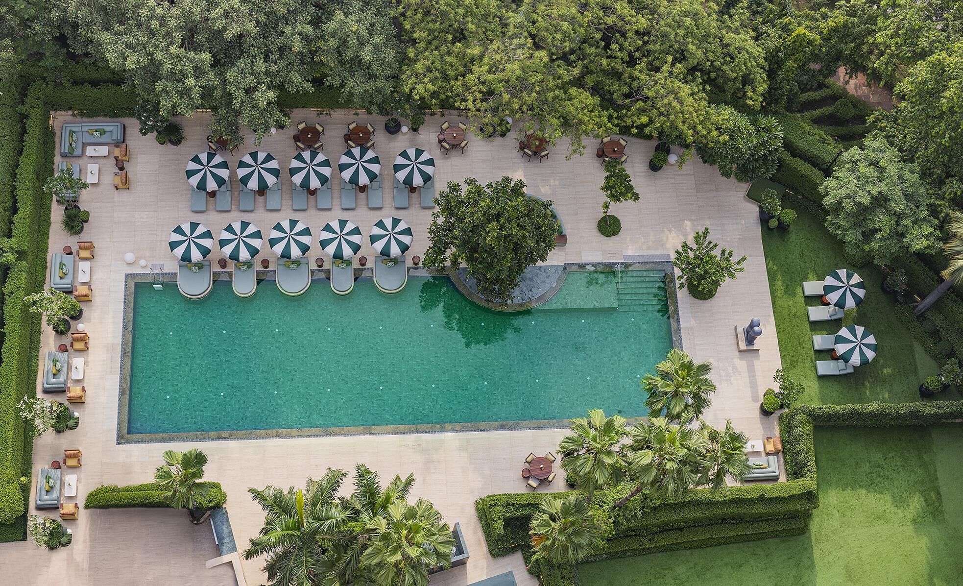 An aerial view of a resort with a swimming pool, sun loungers, and umbrellas.