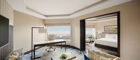 A hotel room with a large bed, a desk, a sofa, a coffee table, and a view of the city.